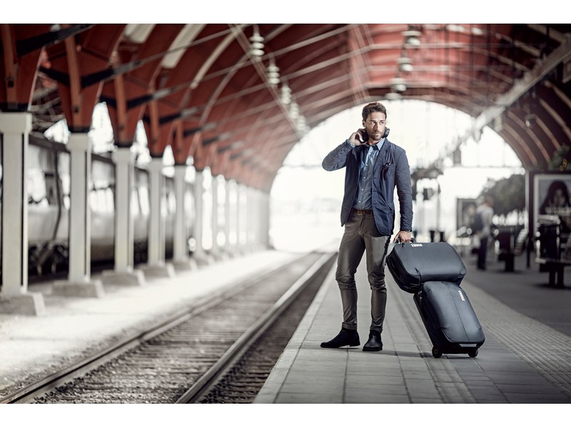 Homme dans une gare avec un bagage cabine à roulettes